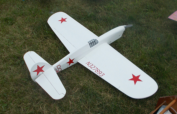 White model airplane with red stars on grass.