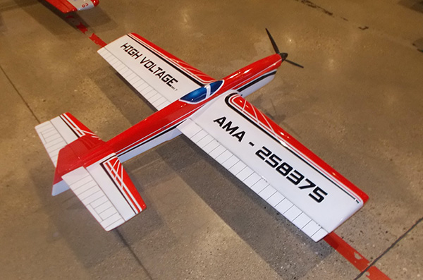 Red and white model airplane on a tiled floor.