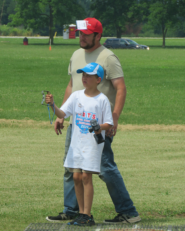 Father and son flying remote-controlled toy outdoors.