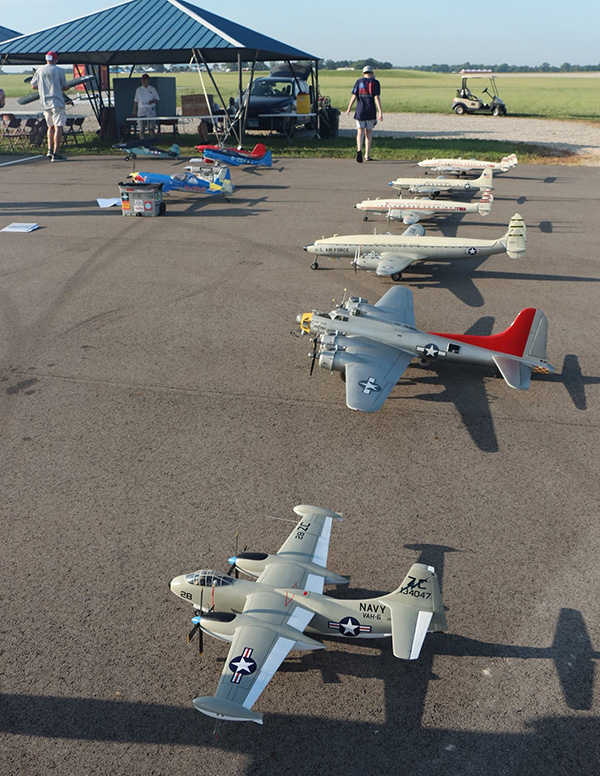 Model airplanes displayed on an airfield under a blue tent.