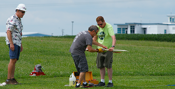 Event Director Dave Edwards watches as Chris starts his engine with Jerry holding. Dave watches for safety concerns; he found on