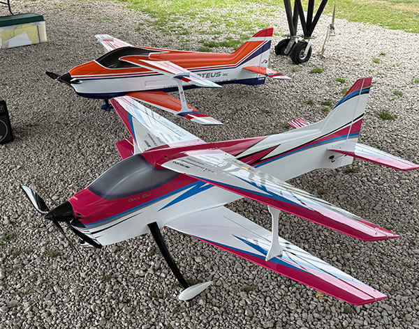 Toy airplanes on gravel, one pink and white, the other orange and white.