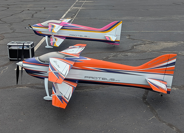 Two colorful model airplanes on an asphalt surface.