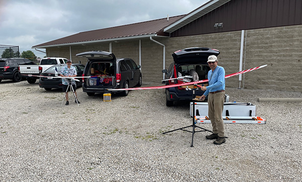 Two people measuring a long pole in a parking area.