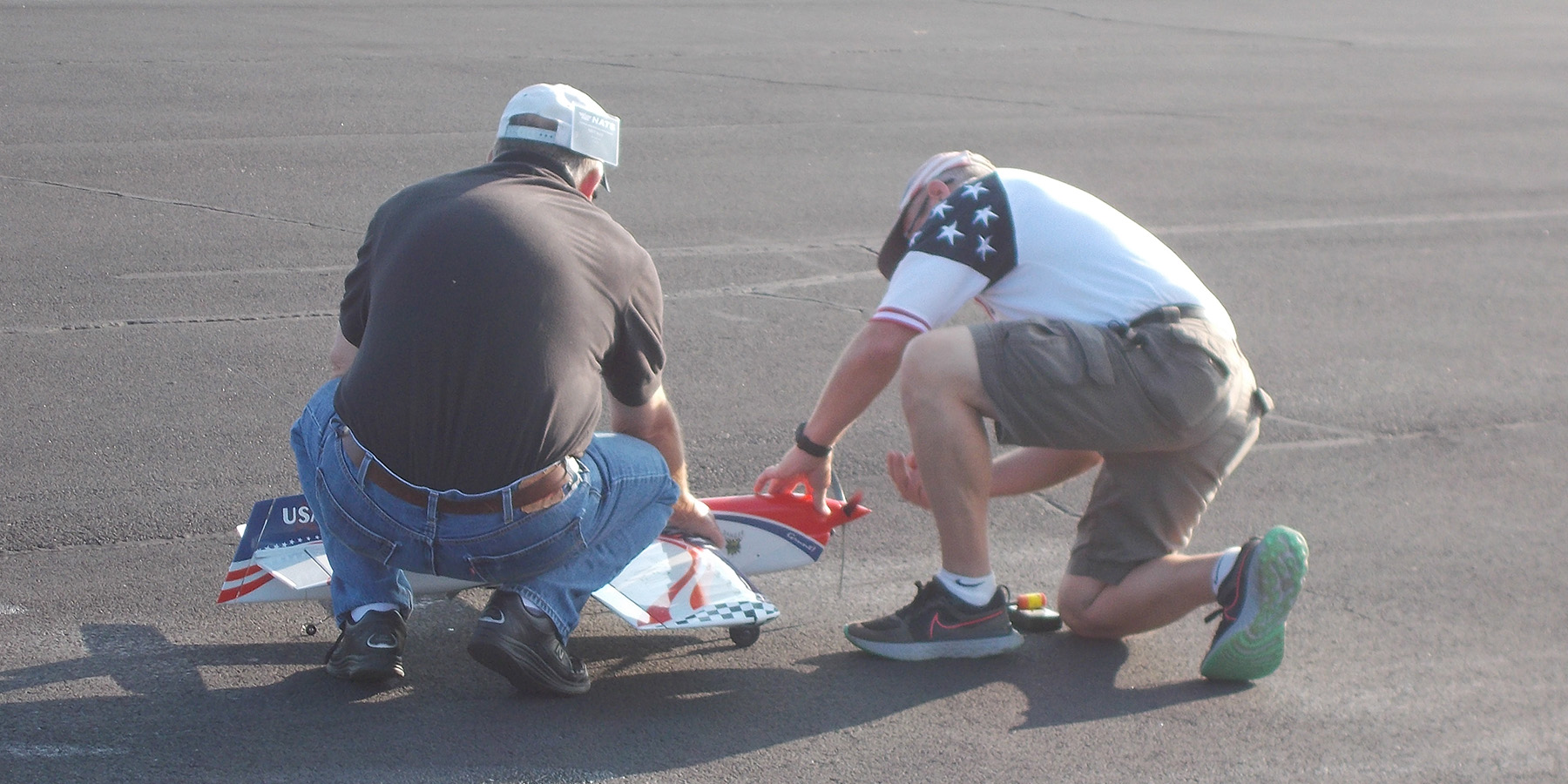 4.	David Fitzgerald prepares his airplane while Brett Buck holds it.