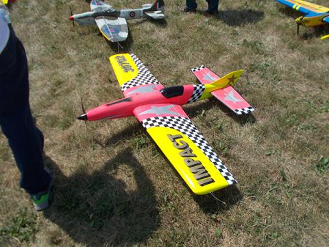 Colorful model airplane on grass, featuring red, yellow, and checkered patterns.