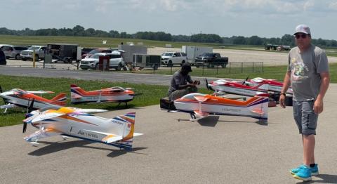 Colorful model airplanes on a runway with two people nearby.