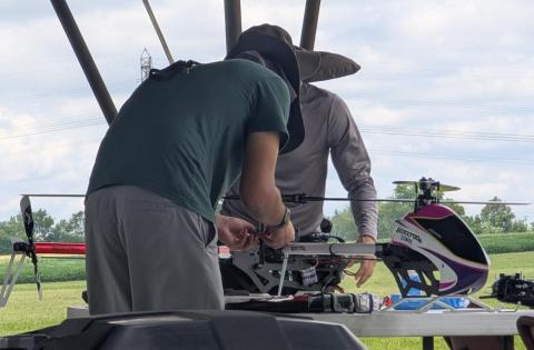 Two people working on a drone helicopter outdoors.