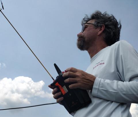 Man flying a remote-controlled device under cloudy sky.