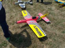 Colorful model airplane on grass, featuring red, yellow, and checkered patterns.